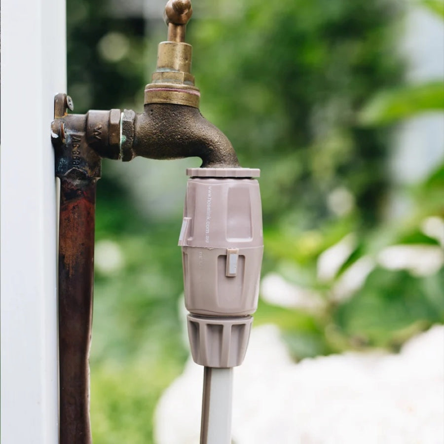 Watering the garden with a Hoselink hose and Comfort spray nozzle, showing real-world water flow from the tap
