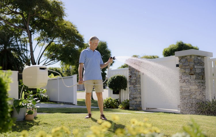 man using Evolve™ Retractable Hose Reel on lawn