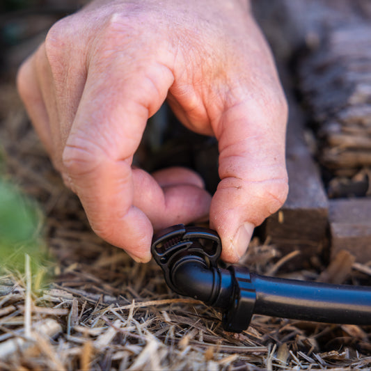 Person tightening 13mm ratchet clamp on black irrigation tubing