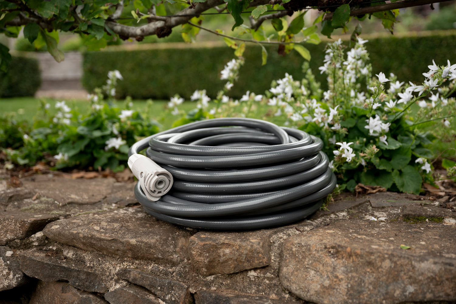 Charcoal-colour Superflex Hose coiled neatly on wall with Hoselink Flow Control Connector fitted to one end