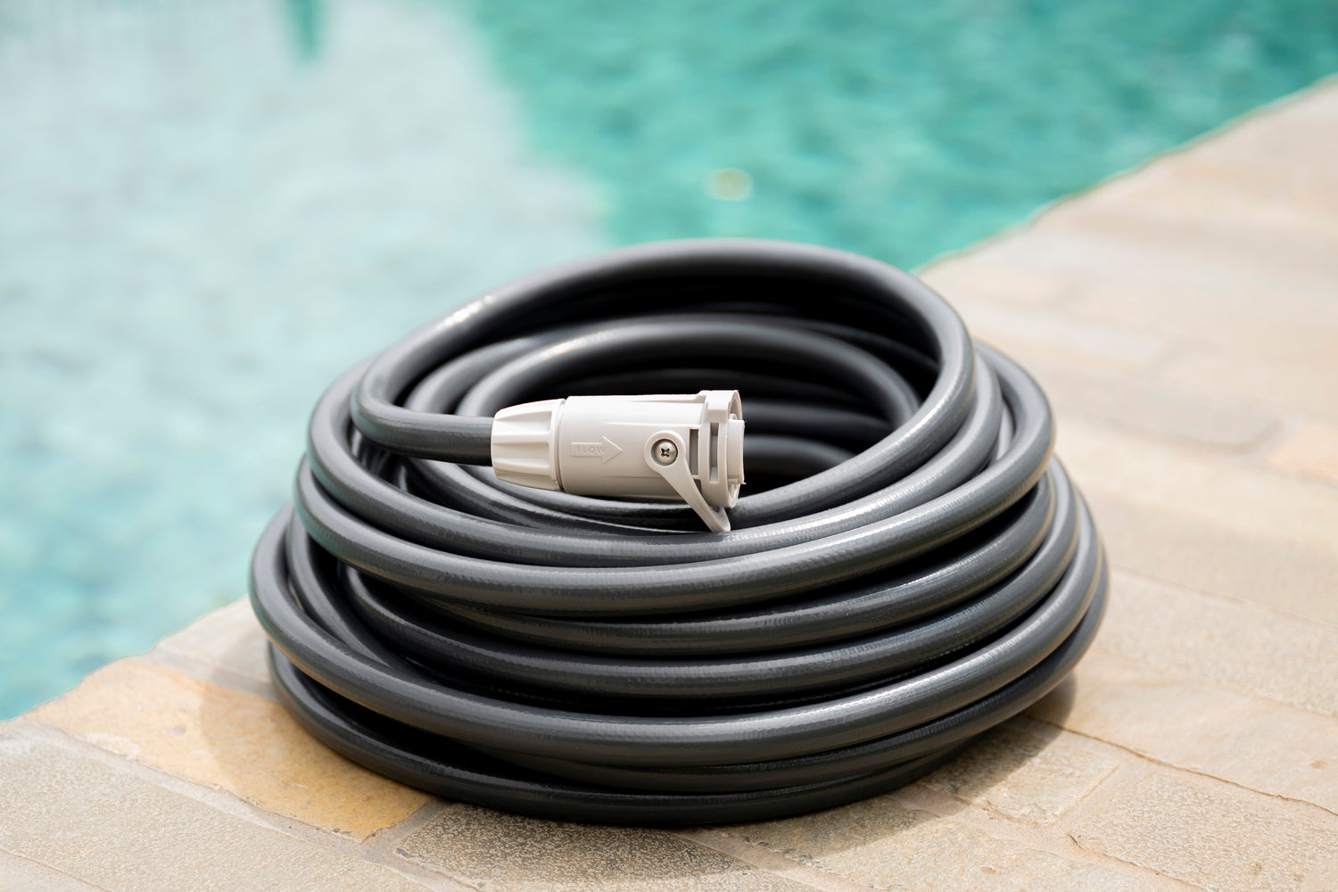 Charcoal Superflex Hose coiled next to pool with Flow Control Connector fitted