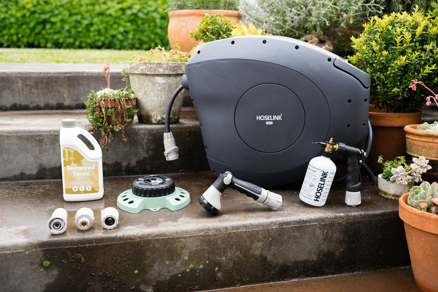 Charcoal Retractable Hose Reel on garden steps with Seaweed Tonic, 9-Pattern Sprinkler, Fertiliser Spray Mixer and Connectors