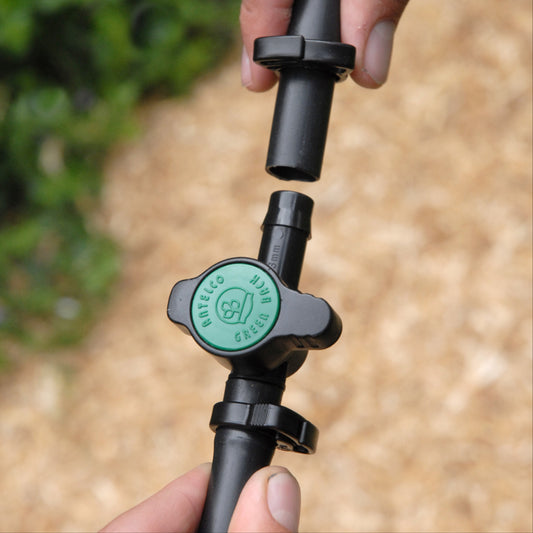 Close up of black and green irrigation valve being attached to irrigation pipe with 13mm ratchet clamps