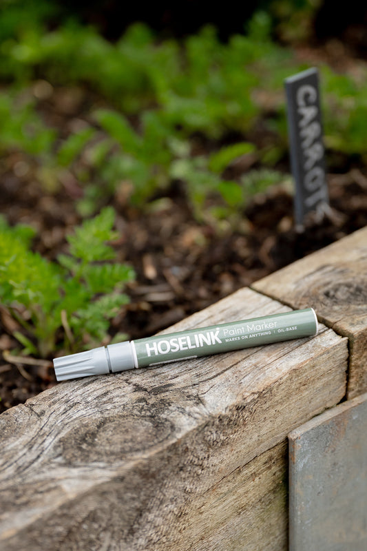 Slate Label Marker Pen sitting on edge of a raised garden bed with slate label and carrots in the background 