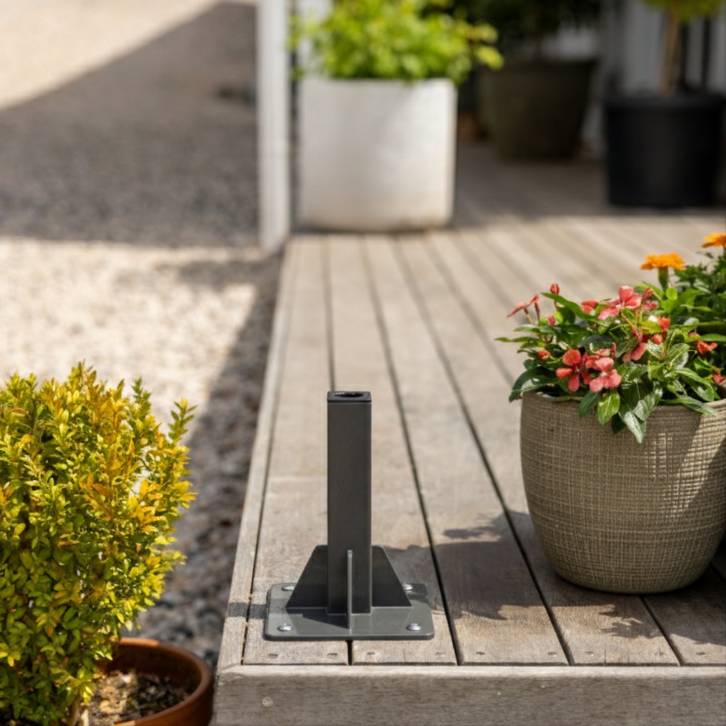 Charcoal classic hose reel grouns mount on the corner of a wooden deck with potted plants either side