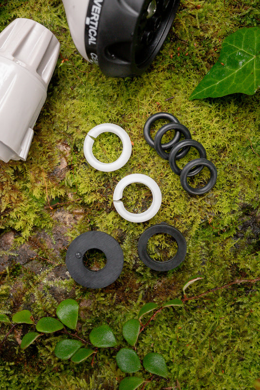 Close-up of Hoselink's Spare O-ring and Washer Set sitting on a mossy background with a Hose End Connector and Spray Gun creeping into shot