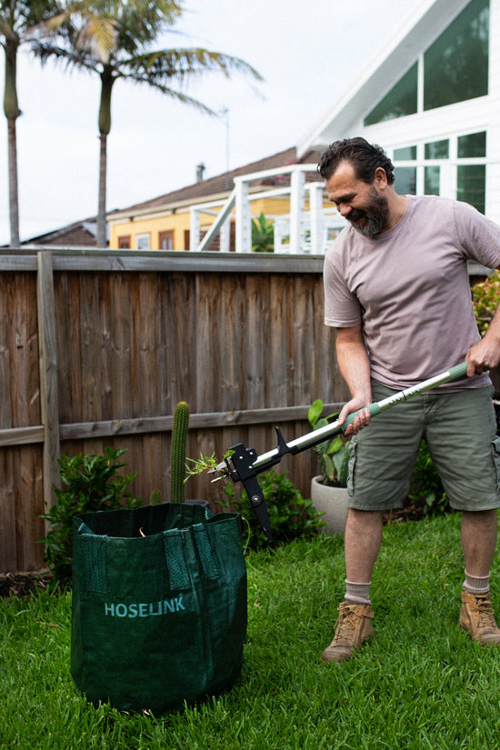 man using stand up weed puller to pull weeds and eject into planter bag