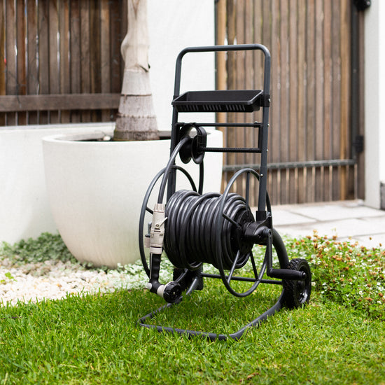 charcoal metal hose reel cart on grass in front garden