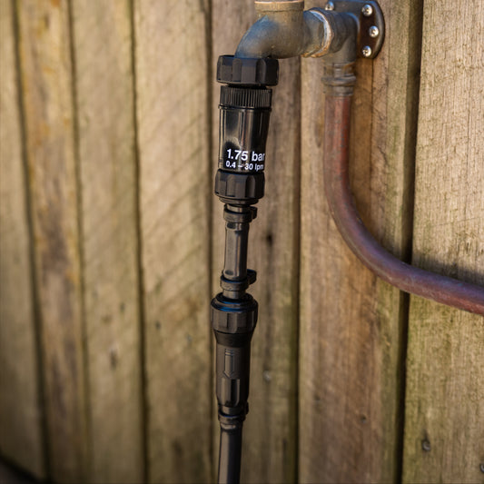 13mm in-line filter attached to poly pipe just below pressure regulator and tap in fromt of a wooden fence