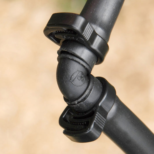 close-up of 13mm elbow joint installed into irrigation tubing with ratchet clamps with blurry light brown background