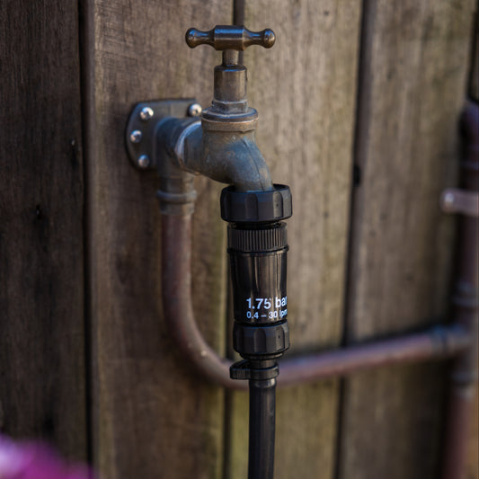 Close up of irrigation pressure regulator, 1" tap adapter and 3/4" nut & tail connecting outdoor tap to poly pipe