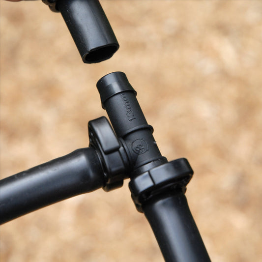 Cloes up of black irrigation tee joint being installed into poly pipe with 13mm ratchet clamp on two of the three ends