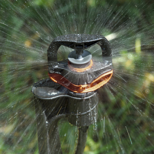 Close up of under tree sprinkler spike watering lawn