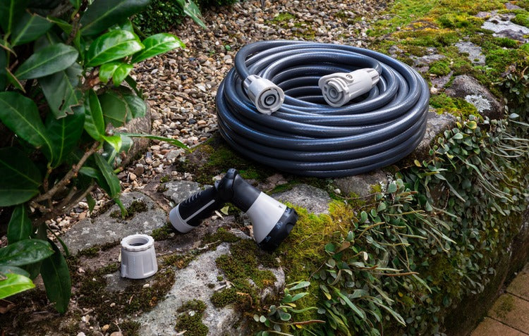 Hose, sprayer and connectors sitting on a rock wall in the garden