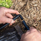 elbow joint beig lined up for nstal into irrigation tubing in a garden bed with straw mulch