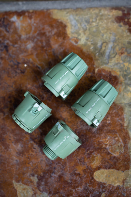 Set of four green 18mm hose connectors arranged neatly together on a stone step