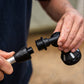 A close-up of a person's hands holding  black plastic 8-pattern sprayer head attachment, being installed on the silver metal telescopic claning system poler, against a blurred outdoor background.