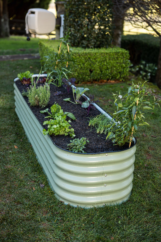 9 in 1 garden bed in long narrow formation on grass with Evolve hose reel in the background.