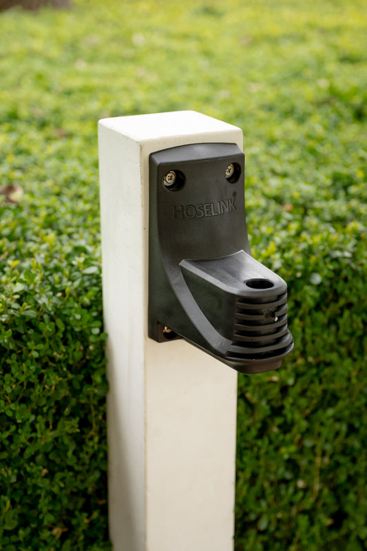 New Hoselink Retractable Hose Reel bracket mounted to a white timber post in garden