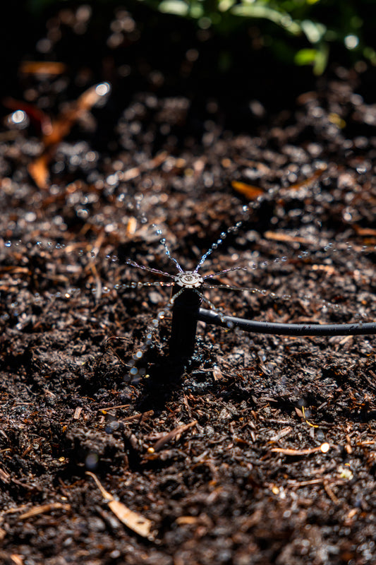 360° adjustable drip spike installed in and watering soil in a garden bed