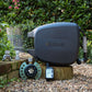 Charcoal evolve hose reel, 9-pattern sprinkler, automatc tap timer, easy turn 2-way adapter and click-on adapter set sitting on a low brick garden wall surrounded by gravel with a green hedge in the background