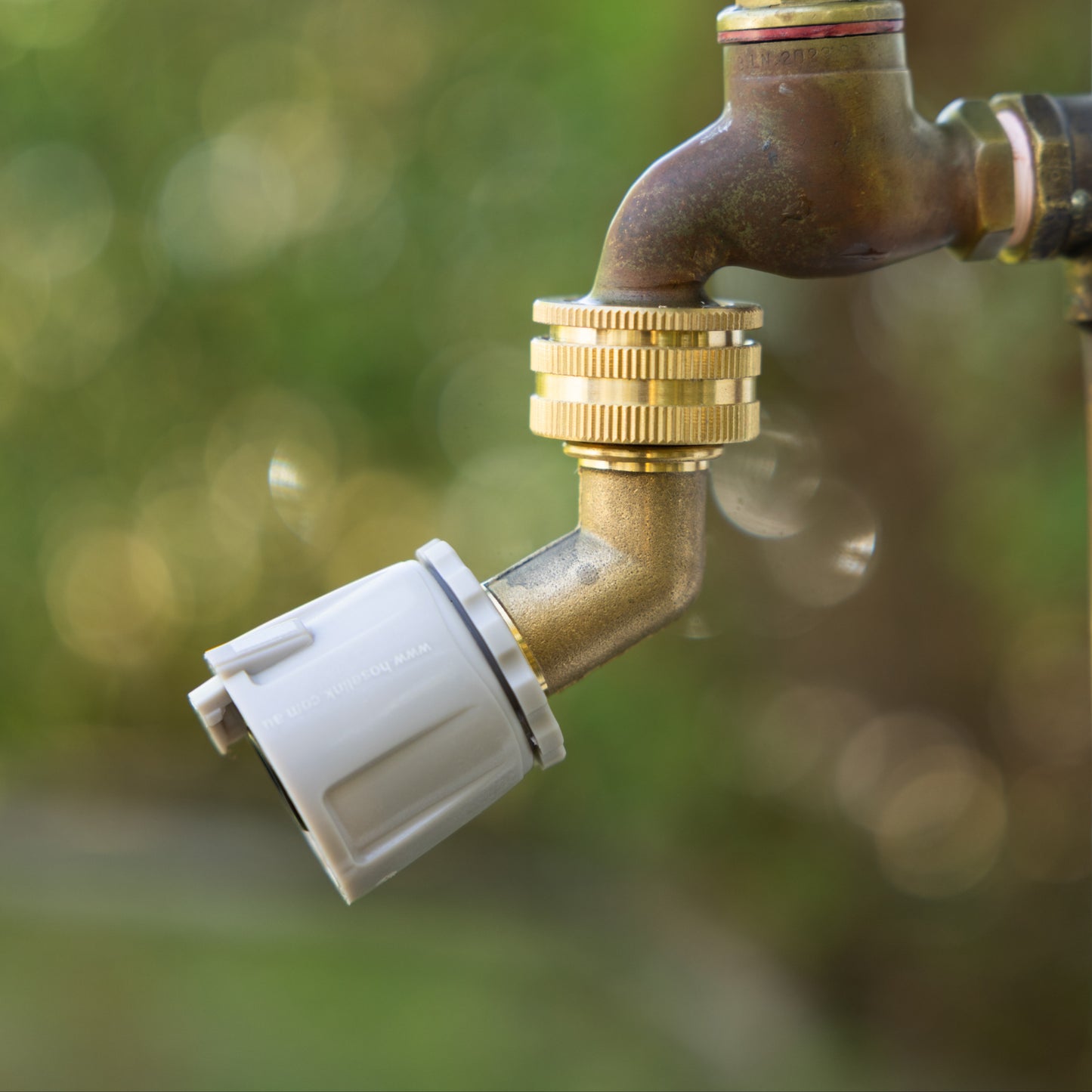 Brass Angled Tap Protector attached to a tap and one end and attached to a Hoselink tap fitting at the other.