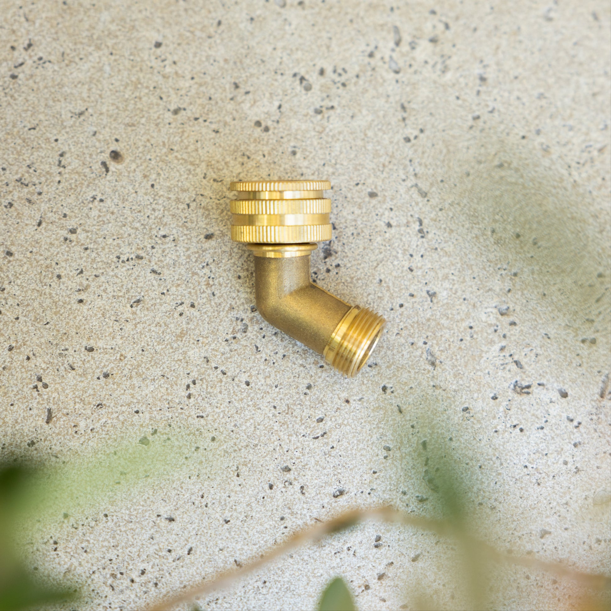 Brass angled tap adaptor lying on a stone background