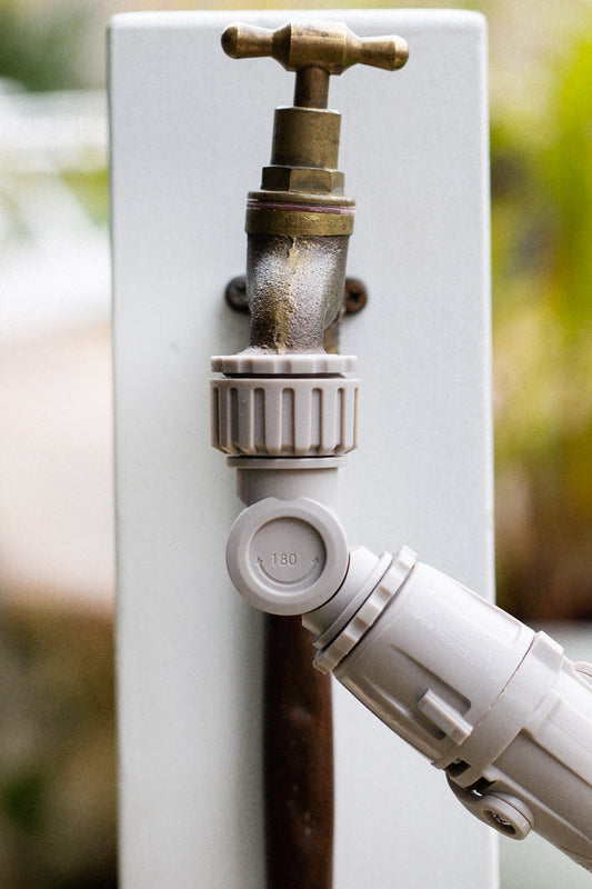 Grey Angled Tap Protector screwed on to a brass outdoor tap at one end, with Hoselink Connectors fitted on the other end.