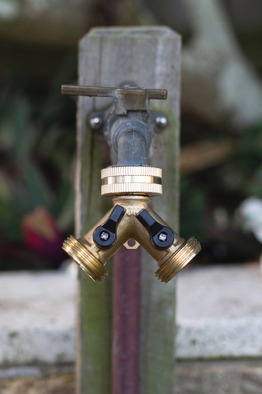 Brass Two Way Tap Adapter attached to an outdoor garden tap, mounted on a wooded post