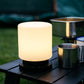 Solar camp light on a black camp table next to camping mugs and burner