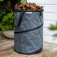 Charcoal coloured Pop up Waste Bag full of brown leaves sitting on a wooden deck