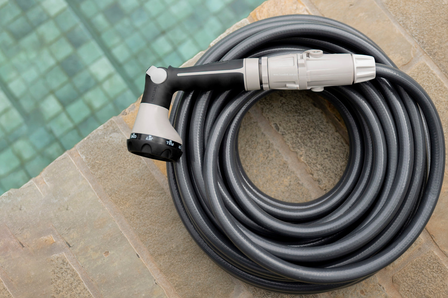 Charcoal Superflex Hose coiled neatly next to pool