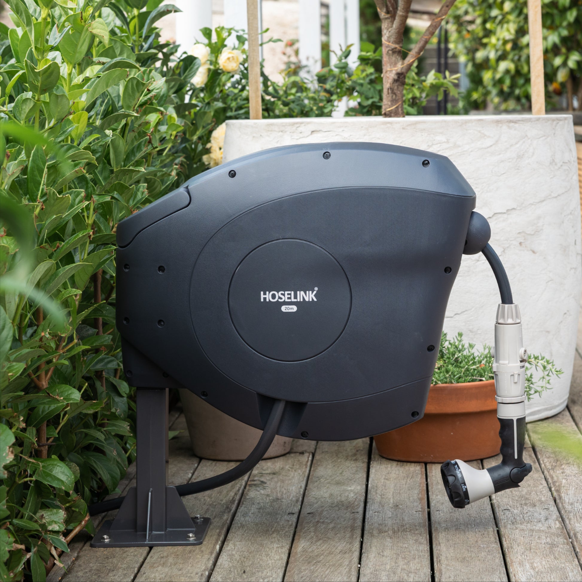 Charocal Hose reel with Hoselink branding mounted on a ground mount on a wooden deck with plants in the background