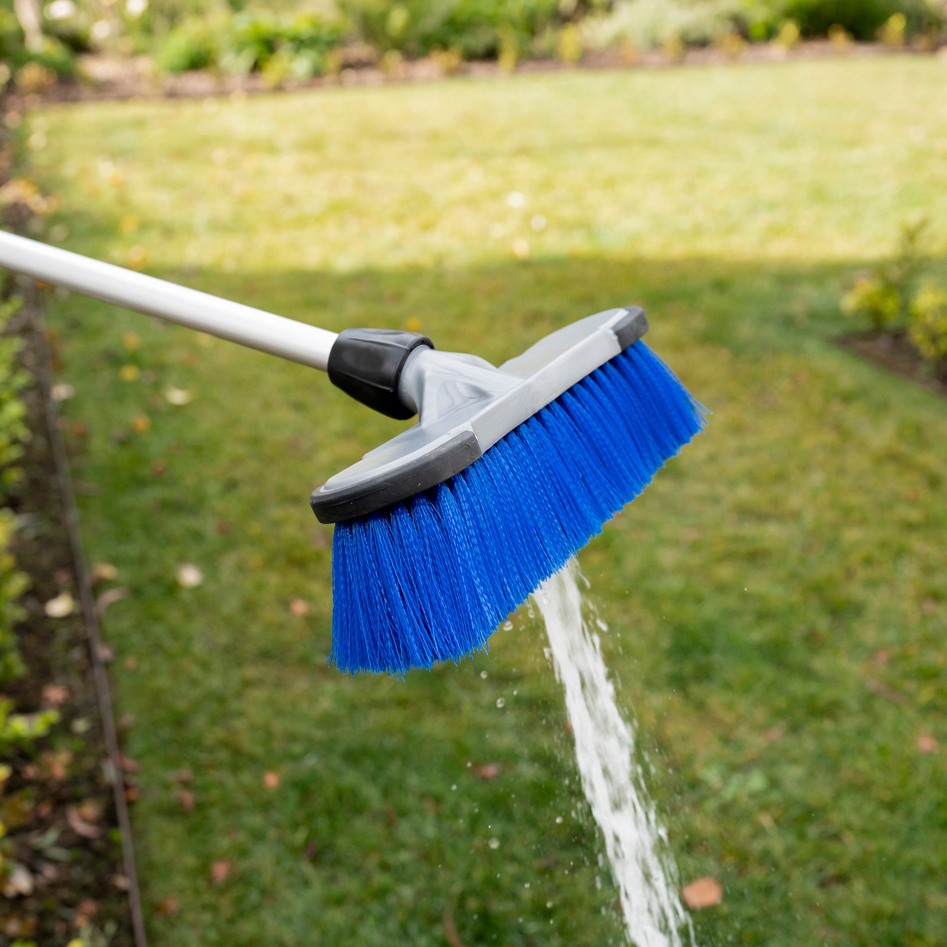 Close up of firm brush head attachment for extendable cleaning brush with water flowing through it