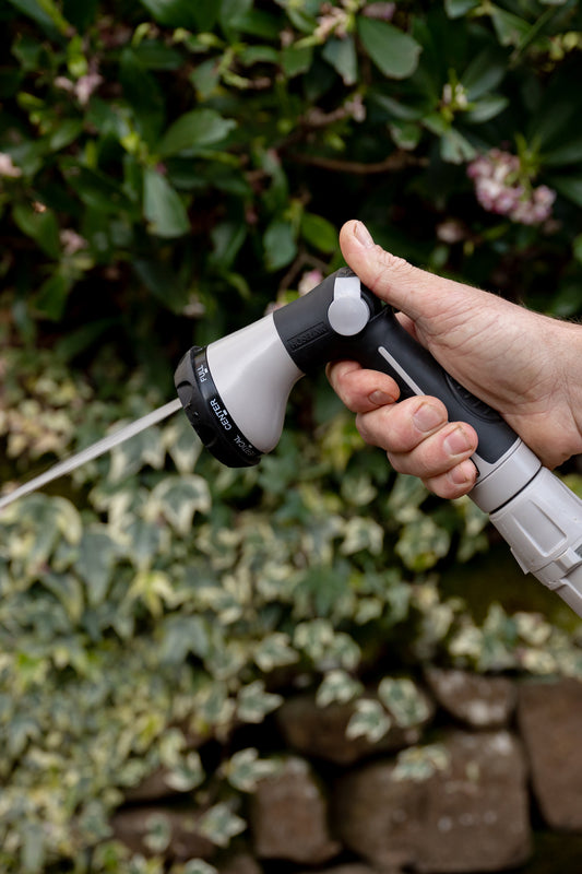Male using Comfort 8-Pattern Flow Control Spray nozzle on jet setting in garden