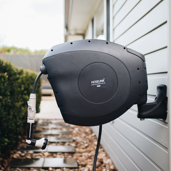 charcoal retractable hose reel mounted on side of house 