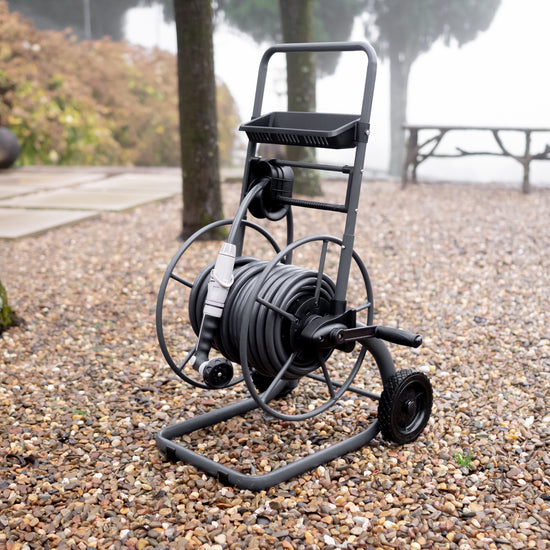 charcoal metal hose reel cart with hose on it on garden pebbles