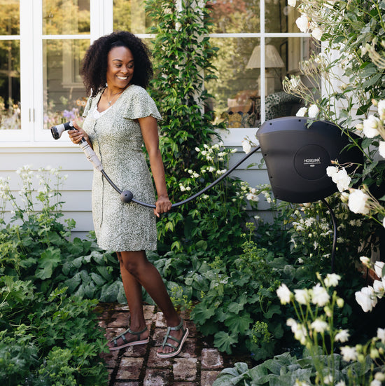 woman using retractable hose reel in garden 