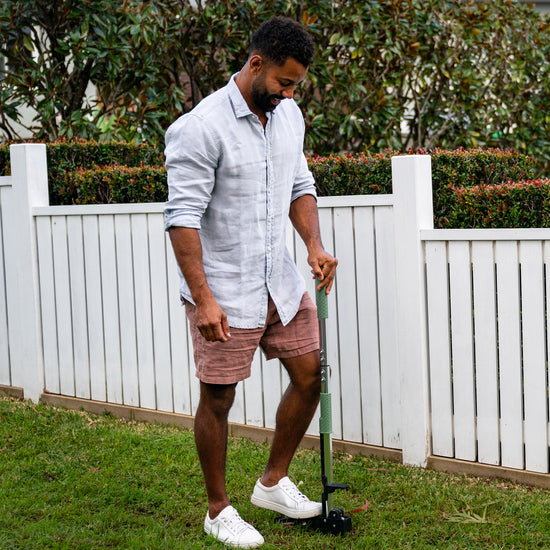 man using stand up weed puller to pull weeds from front lawn