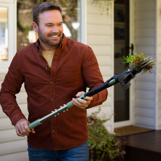 man ejecting weed from stand up weed puller in front yard