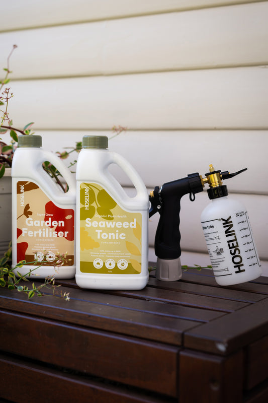 garden fertiliser and seaweed tonic next to fertiliser spray mixer on timber bench