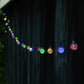 String of colorful outdoor lights against a dark wooden fence