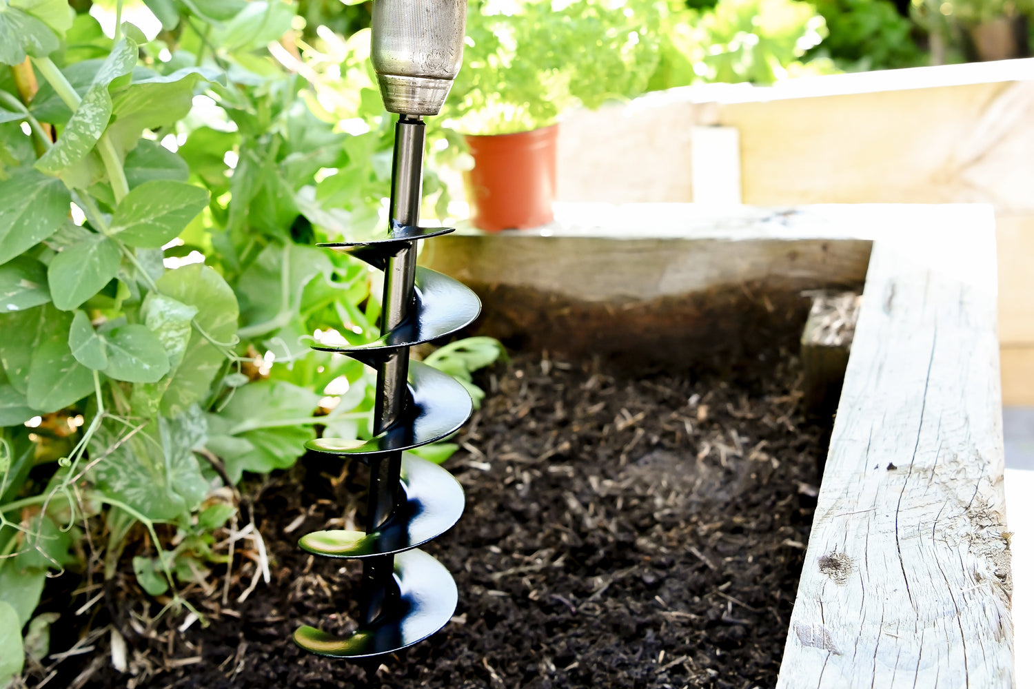garden drill auger being used in raised veggie bed 