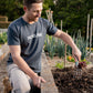 Man gardening in a plot with garden fork tool wearing a HOSELINK shirt.