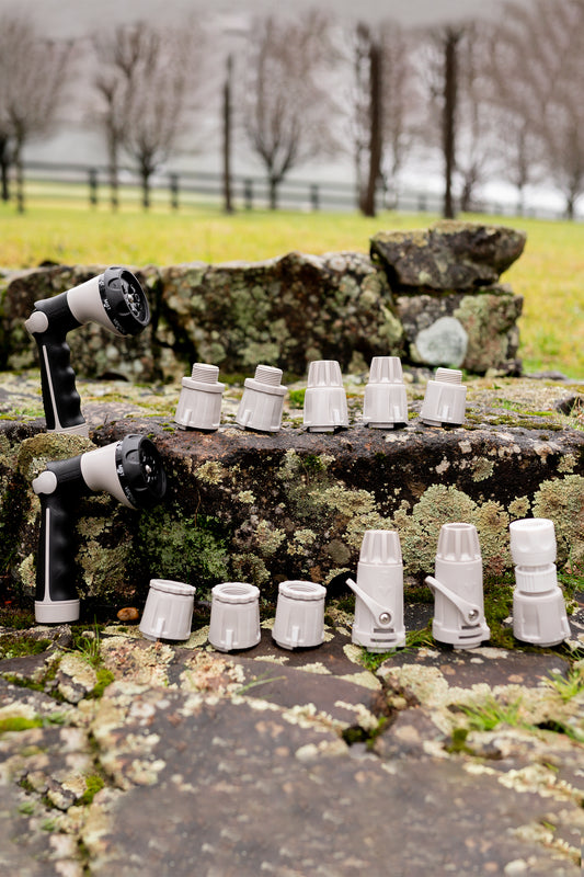 An assortment of Hoselink Hose Connectors on stone steps in the garden with two Comfort 8-Pattern Spray Guns