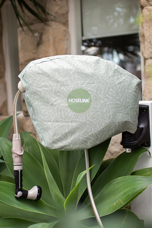 Green natural fern hose reel cover on Retractable Hose Reel mounted to a white timber post in front garden