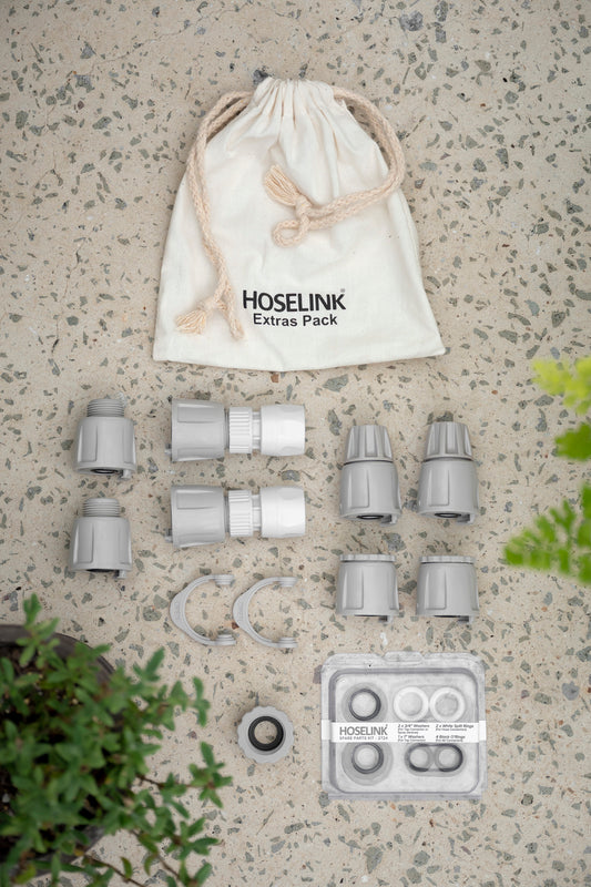 Pack of 12 spare parts and Hoselink connectors arranged on floor with calico drawstring bag and plants