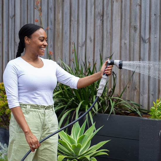 Female watering in the garden with the Charcoal Superflex Hose and 8-Pattern Spray Gun
