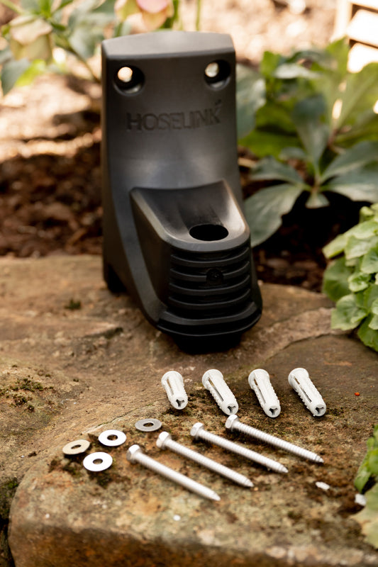 Retractable Hose Reel Bracket sitting on garden wall with screws, washers and plugs laid out in front of it