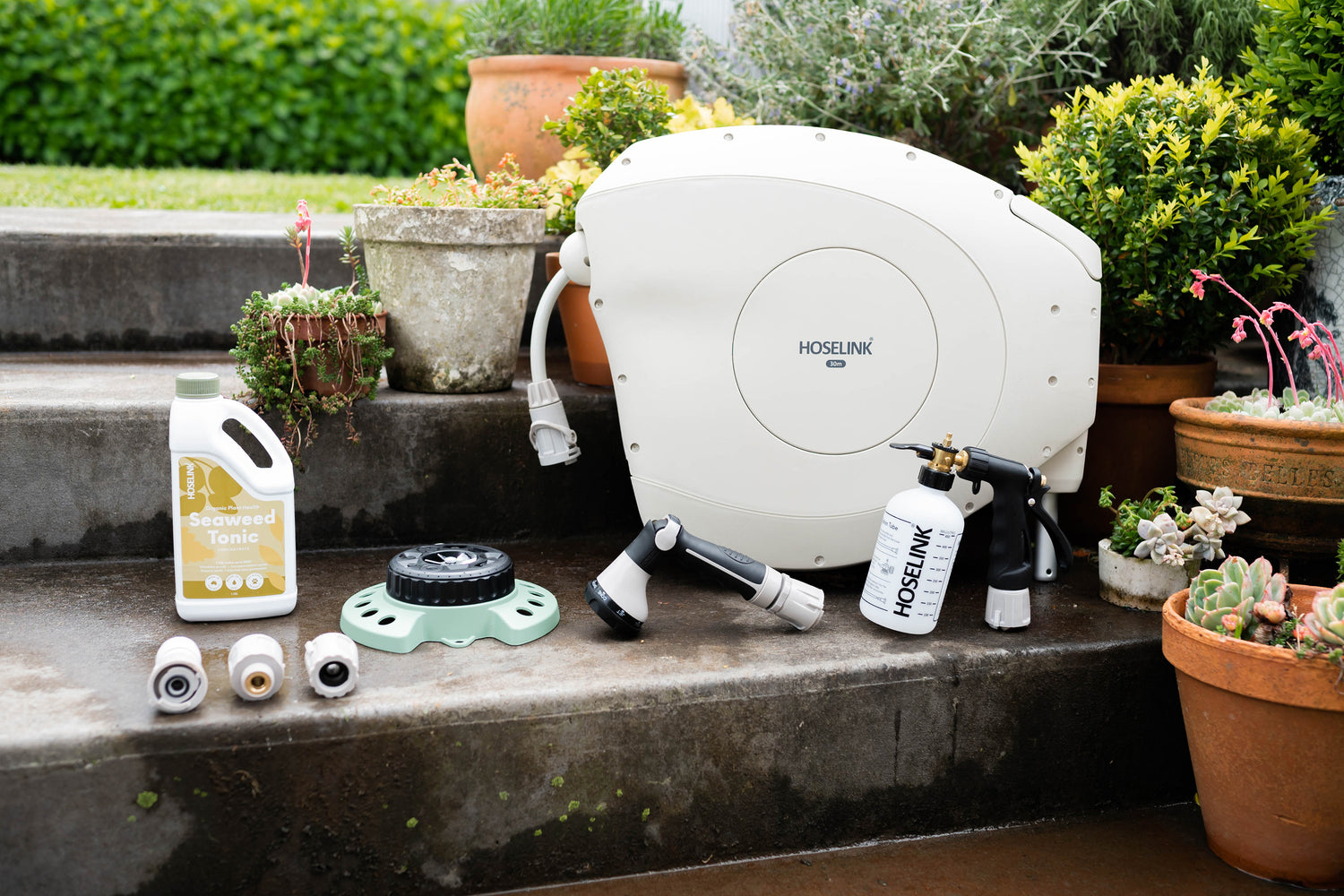 Beige Retractable Hose Reel on garden steps with Seaweed Tonic, 9-Pattern Sprinkler, Fertiliser Spray Mixer and Connectors